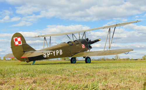 Dwupłatowy radziecki samolot wielozadaniowy Polikarpov czekający na wycieczkowy lot nad przedmieściami Warszawy.
